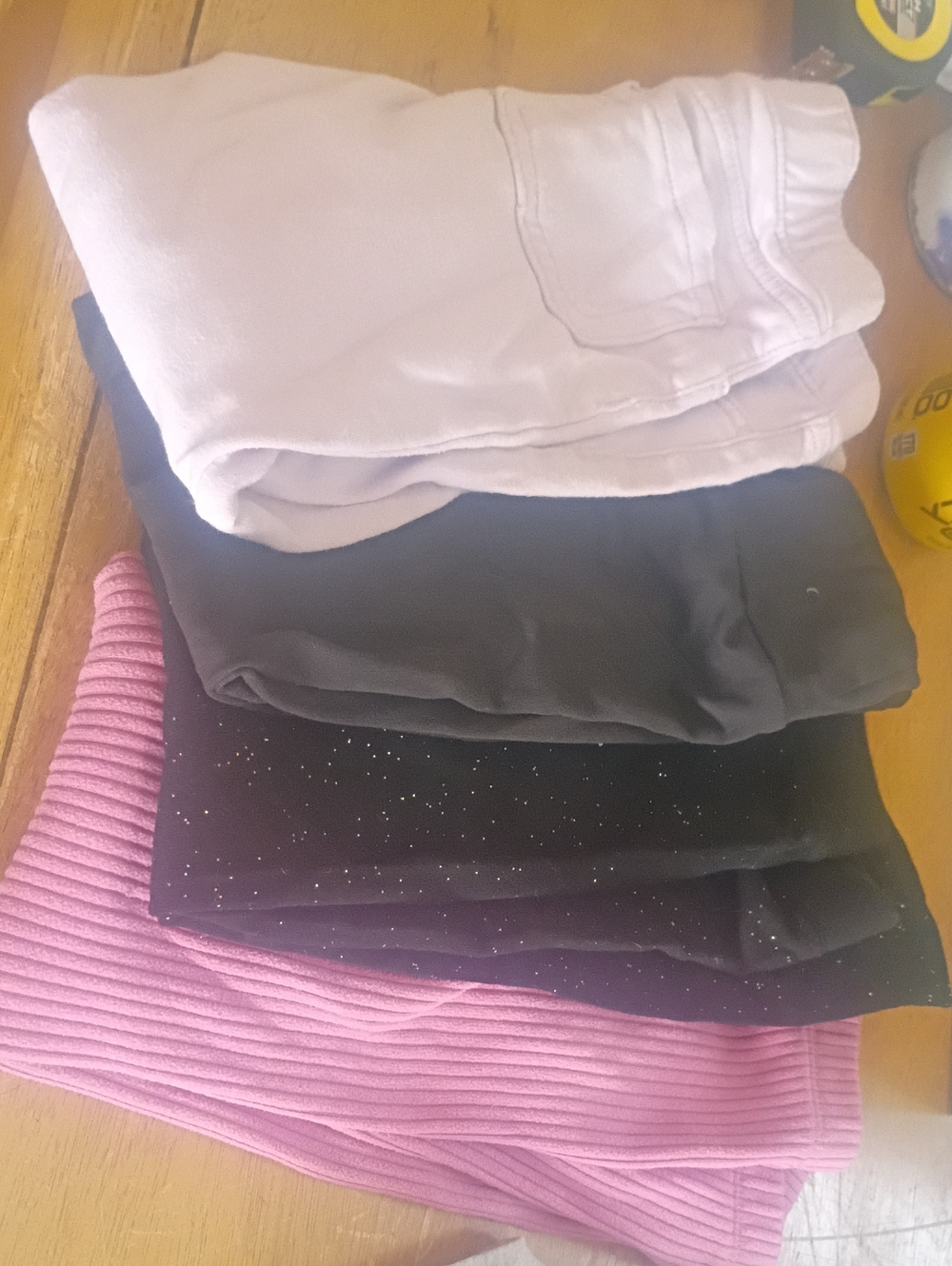 Stack of Folded Pants and Skirts in Light Pink, Black and Lavender